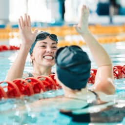 Two women high fiving across swimming lanes
