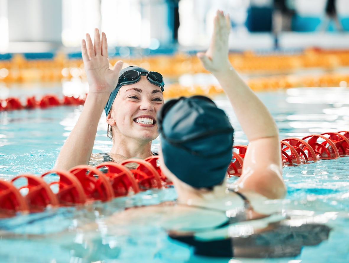 Two women high fiving across swimming lanes