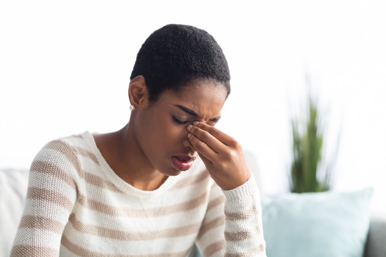 Woman holding the bridge of her nose frowning