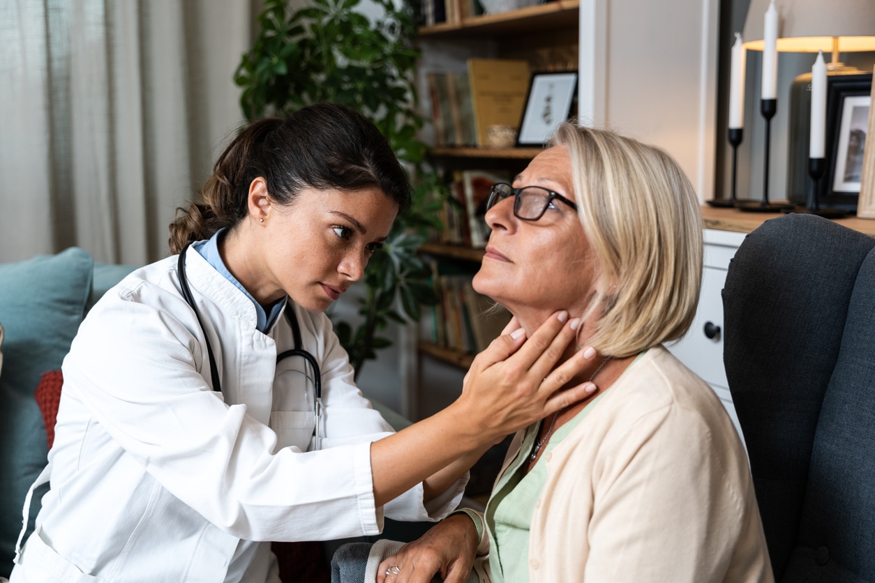 Doctor feeling a patient's throat.