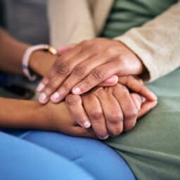 Close up of people holding hands, consoling each other.