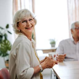 Senior woman posing for camera while sitting at the table at home
