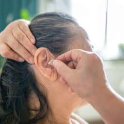 Senior woman putting on her hearing aid.