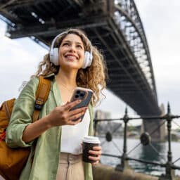 Young woman walking along the river listening to music with her headphones.