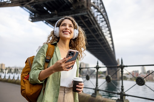Young woman walking along the river listening to music with her headphones.