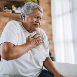 Woman with heartburn putting her hand on her chest.