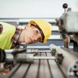 Women with protective equipment working on the drill in factory plant
